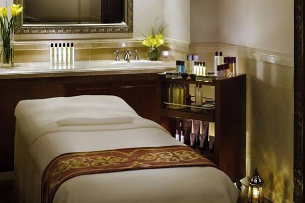 Luxuriöser Spa-Behandlungsraum im Palace At One & Only Royal Mirage mit Massageliege, Waschbecken und Kosmetikprodukten.