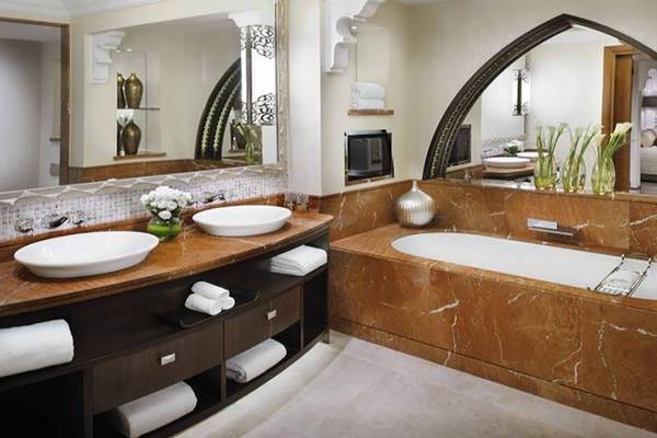 Das Badezimmer im Hotel The Palace At One & Only Royal Mirage mit Marmorfliesen, zwei Waschbecken, Badewanne und Spiegeln.
