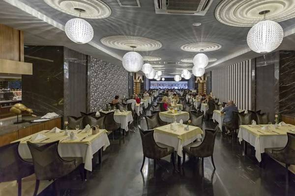 Innenansicht des Restaurants im Royal Holiday Palace mit runden Kronleuchtern und vollen Tischen.