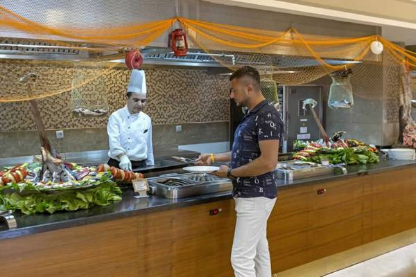 Buffetbereich im Royal Holiday Palace mit zwei Köchen und einem Gast, der Speisen auswählt.