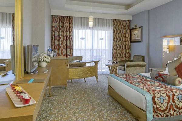 Hotelzimmer des Royal Holiday Palace mit Doppelbett, Fernseher, Tisch und Stühle.