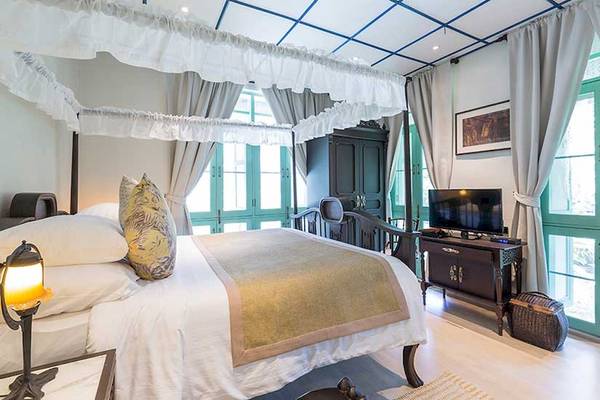 Schlafzimmer im Cape Panwa Hotel mit Baldachinbett, Fernseher und Nachttischlampe.