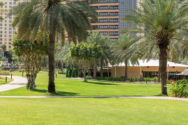 Gartenansicht des Le Royal Meridien Beach Resort & Spa mit hohen Gebäuden im Hintergrund