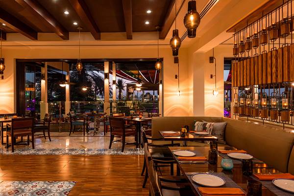 Innenansicht des Restaurants im Le Royal Meridien Beach Resort & Spa mit Tischen, Stühlen und einer gemütlichen Atmosphäre.
