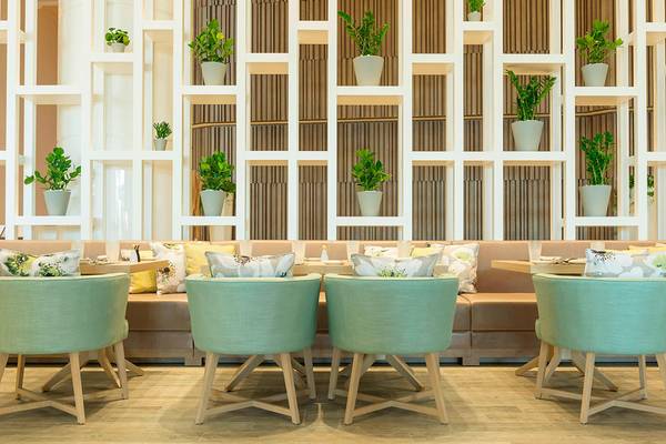 Inneneinrichtung des Le Royal Meridien Beach Resort & Spa mit grünen Stühlen und Pflanzen an der Wand.