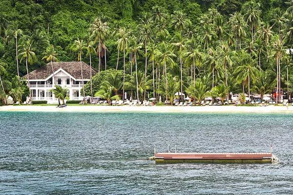 Cape Panwa Hotel am Strand mit vielen Palmen und Lounge-Stühlen