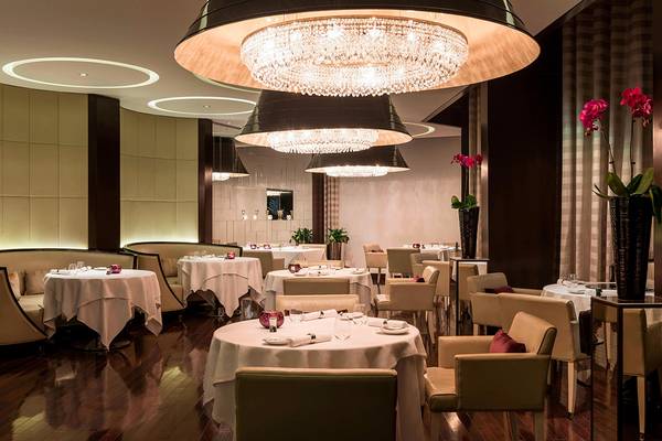 Innenansicht des Restaurants im Le Royal Meridien Beach Resort & Spa mit eleganten Tischen und Kristalllampen.