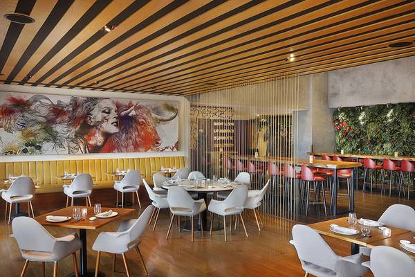 Innenansicht des Restaurants im Westin Dubai Mina Seyahi Beach Resort & Marina mit Kunstwerk an der Wand, Holzboden und modernen Möbeln.