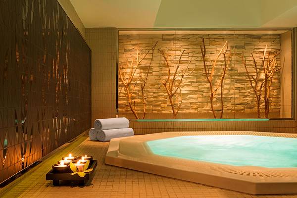 Innenjacuzzi im Westin Dubai Mina Seyahi Beach Resort & Marina mit steinerner Wand und Kerzen.