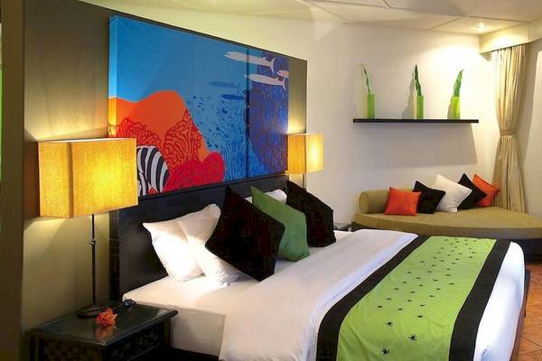 Hotelzimmer im Angsana Velavaru mit großen Gemälden, bequemem Bett und Sofa