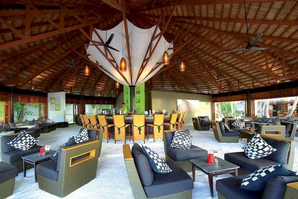 Loungebereich im Angsana Velavaru Hotel mit weißer Sandboden und blauen Sofas.