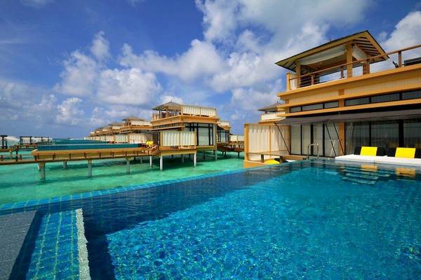 Außenpool im Angsana Velavaru Hotel mit Wasservillen im Hintergrund.