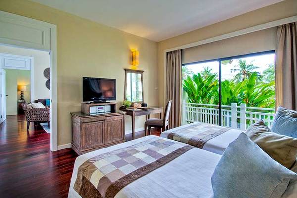 Doppelzimmer im Cape Panwa Hotel mit zwei Betten, Fernseher, Schreibtisch und Balkon.