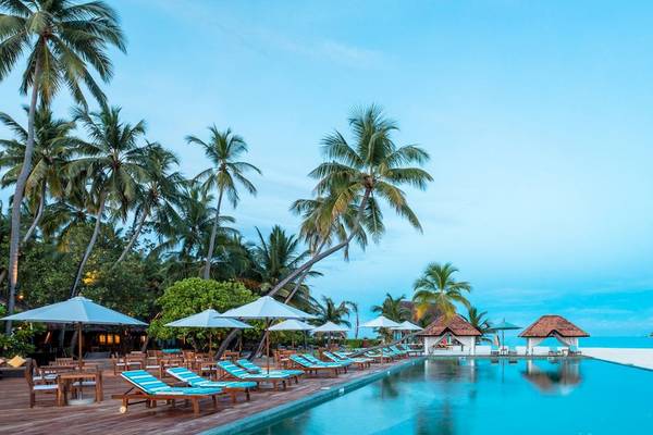 Außenpool des Angsana Velavaru Hotels mit Sonnenliegen und Palmen