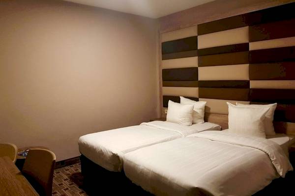 Doppelbettzimmer im XO Hotels Blue Square mit zwei weißen Betten und Kopfteilen.