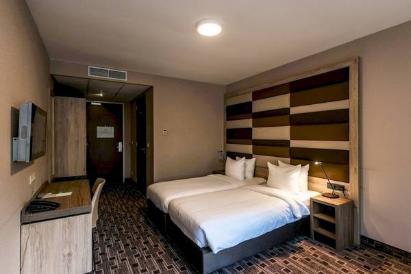 Zimmer im XO Hotels Blue Square mit zwei Betten, Schreibtisch und Fernseher.