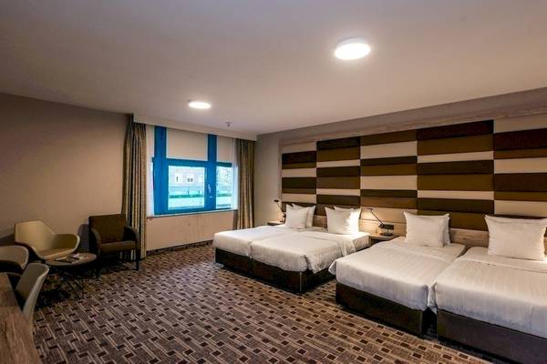 Doppelzimmer im XO Hotels Blue Square mit drei Betten, Fenster und Möbeln.