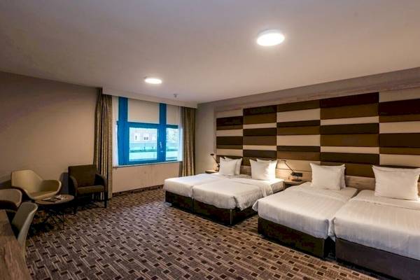 Doppelzimmer im XO Hotels Blue Square mit drei Betten, Fenstern und Möbeln.