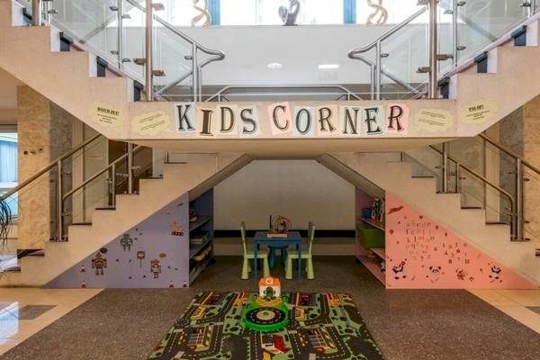 XO Hotels Blue Square mit einem Bereich für Kinder, gekennzeichnet durch die Wandbemalung und das Schild 'Kids Corner'.