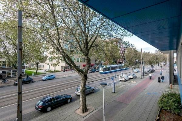Eine Straße mit einer Straßenbahn und Autos, vor dem XO Hotels Blue Square.