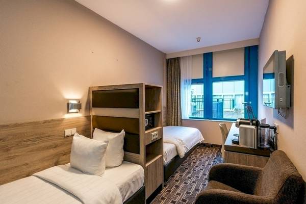 Zimmer im XO Hotels Blue Square mit zwei Betten, Fernseher und Schreibtisch.