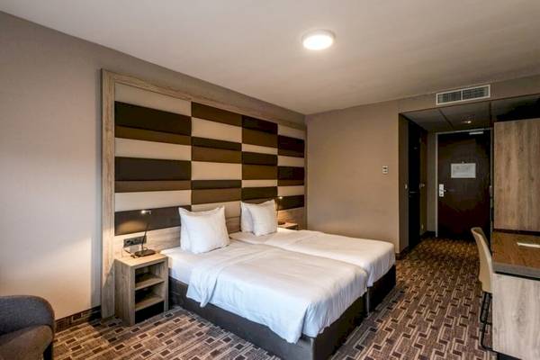 Doppelzimmer im XO Hotels Blue Square mit zwei Betten, Nachttischen und einem gemusterten Wanddesign.