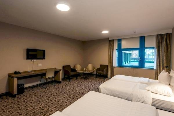 Schlafzimmer im XO Hotels Blue Square mit drei Betten, Fernseher und Schreibtisch
