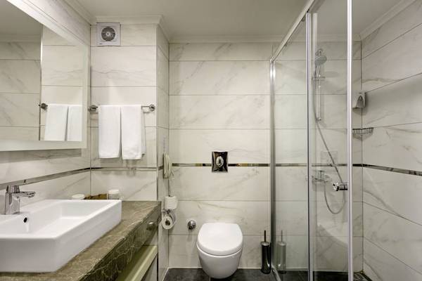Badezimmer im Glamour Resort & Spa mit Marmorwänden, Dusche, Toilette und Waschbecken.