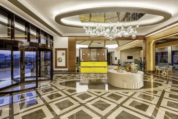 Empfangshalle des Glamour Resort & Spa mit Marmorboden, Kronleuchter und Rezeptionstresen