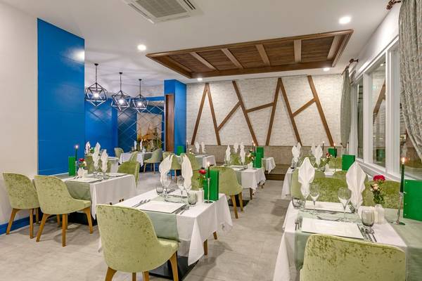 Innenansicht des Gastronomiebereichs im Glamour Resort & Spa mit blauen Wänden und grünen Stühlen.