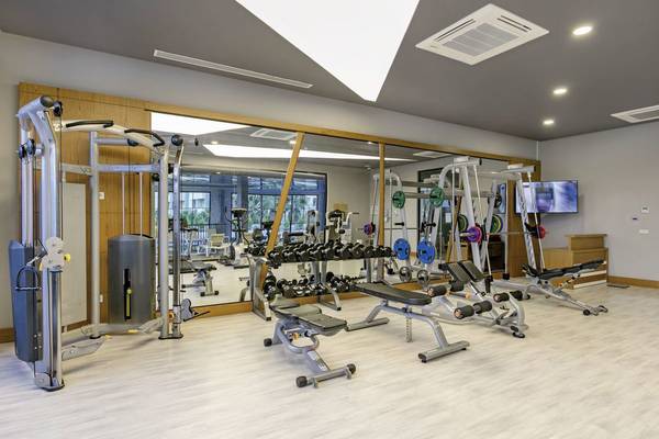 Fitnessstudio im Glamour Resort & Spa mit verschiedenen Geräten und einer Glaswand.