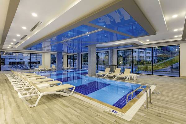 Innenpool des Glamour Resort & Spa mit blauem Glasdach und Sonnenliegen