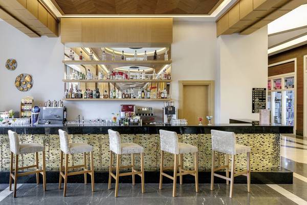 Innenansicht der Bar im Glamour Resort & Spa mit Barhockern und einer Theke.