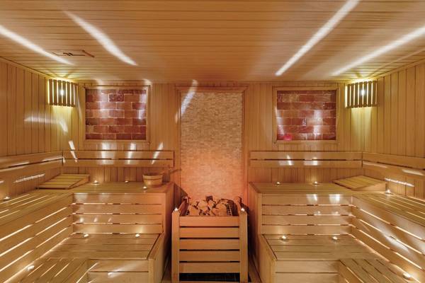Sauna im Glamour Resort & Spa mit hölzernen Bänken und Feuerstelle.