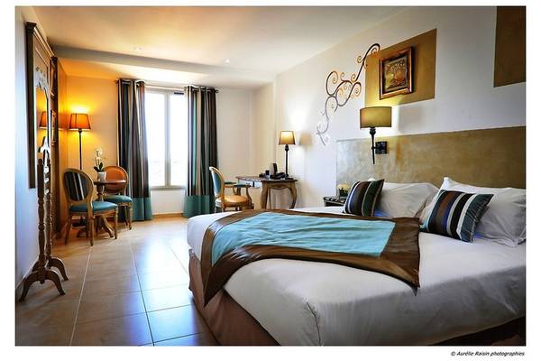 Innenansicht eines Boutique Hotelzimmers mit einem Bett, Möbeln und Wanddekorationen.
