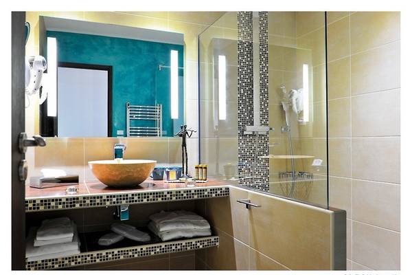 Ein Badezimmer im Boutique Hotel Liberata mit einer Dusche, einem Waschbecken und Handtüchern.