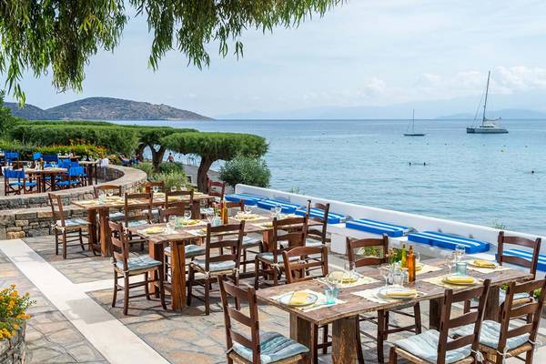 Außenterrasse des Elounda Bay Palace Hotels mit Blick auf das Meer und Segelboote.