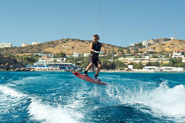 Ein Kitesurfer auf dem Wasser mit einem Hotel im Hintergrund.