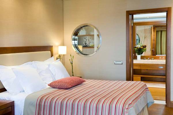 Schlafzimmer im Elounda Bay Palace Hotel mit einem Bett, Kissen und einer Lampe.