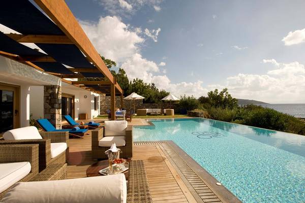 Poolbereich des Elounda Bay Palace Hotels mit Lounge-Möbeln und Meerblick.