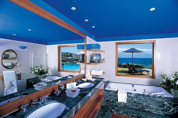 Badezimmer im Elounda Bay Palace Hotel mit Blick auf den Pool und das Meer.
