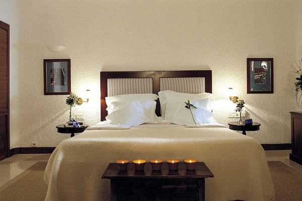 Schlafzimmer im Elounda Bay Palace Hotel mit Bett, Kissen und Kerzen.
