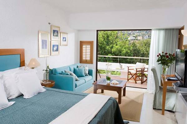 Schlafzimmer im Elounda Bay Palace Hotel mit Blick auf einen Balkon und eine Terrasse.
