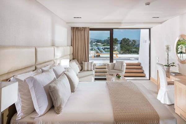 Innenansicht der Suite im Elounda Bay Palace mit großem Bett, Aussichtsfenster und Wohnzimmerbereich.