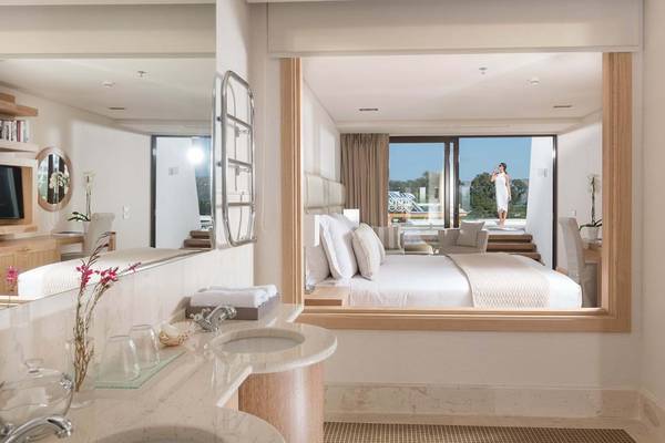 Elounda Bay Palace Hotel Badezimmer mit Bett und Spiegel im Hintergrund