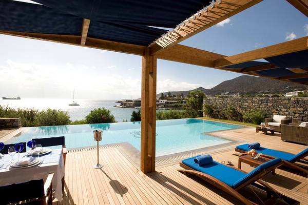 Pool-Terrasse im Elounda Bay Palace mit Blick auf das Meer und eine Insel.