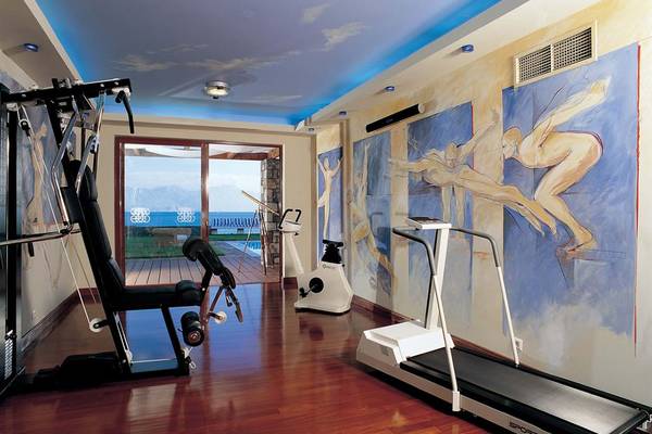 Fitnessbereich im Elounda Bay Palace Hotel mit Blick auf das Meer und einem Pool.