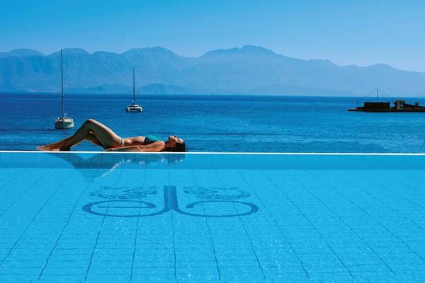 Eine Frau entspannt am Rand eines Swimmingpools im Elounda Bay Palace Hotel.