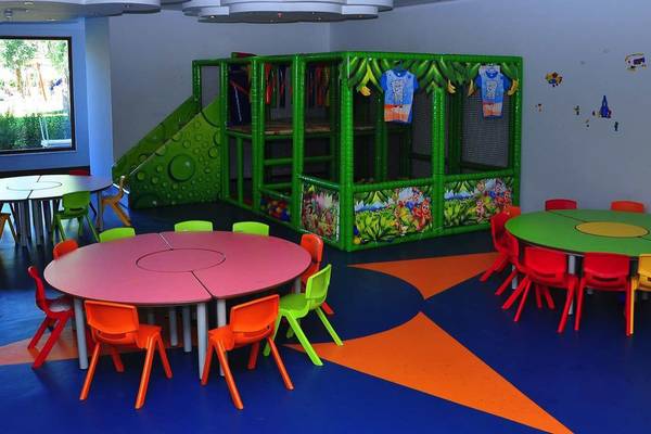 Kinderspielplatz im Primasol Hane Family Resort mit bunten Tischen, Stühlen und einer großen grünen Spielburg.