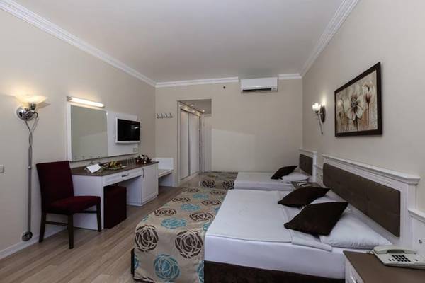 Doppelzimmer-Innenansicht des Primasol Hane Family Resort mit zwei Betten, Schreibtisch und Fernseher.